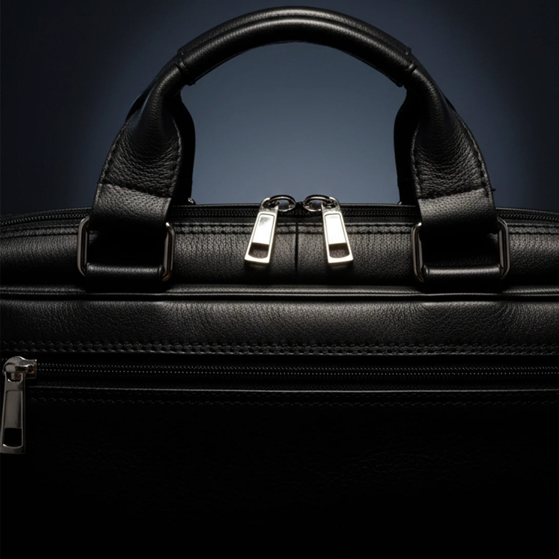 close-up of black leather bag handle and zipper in dark background