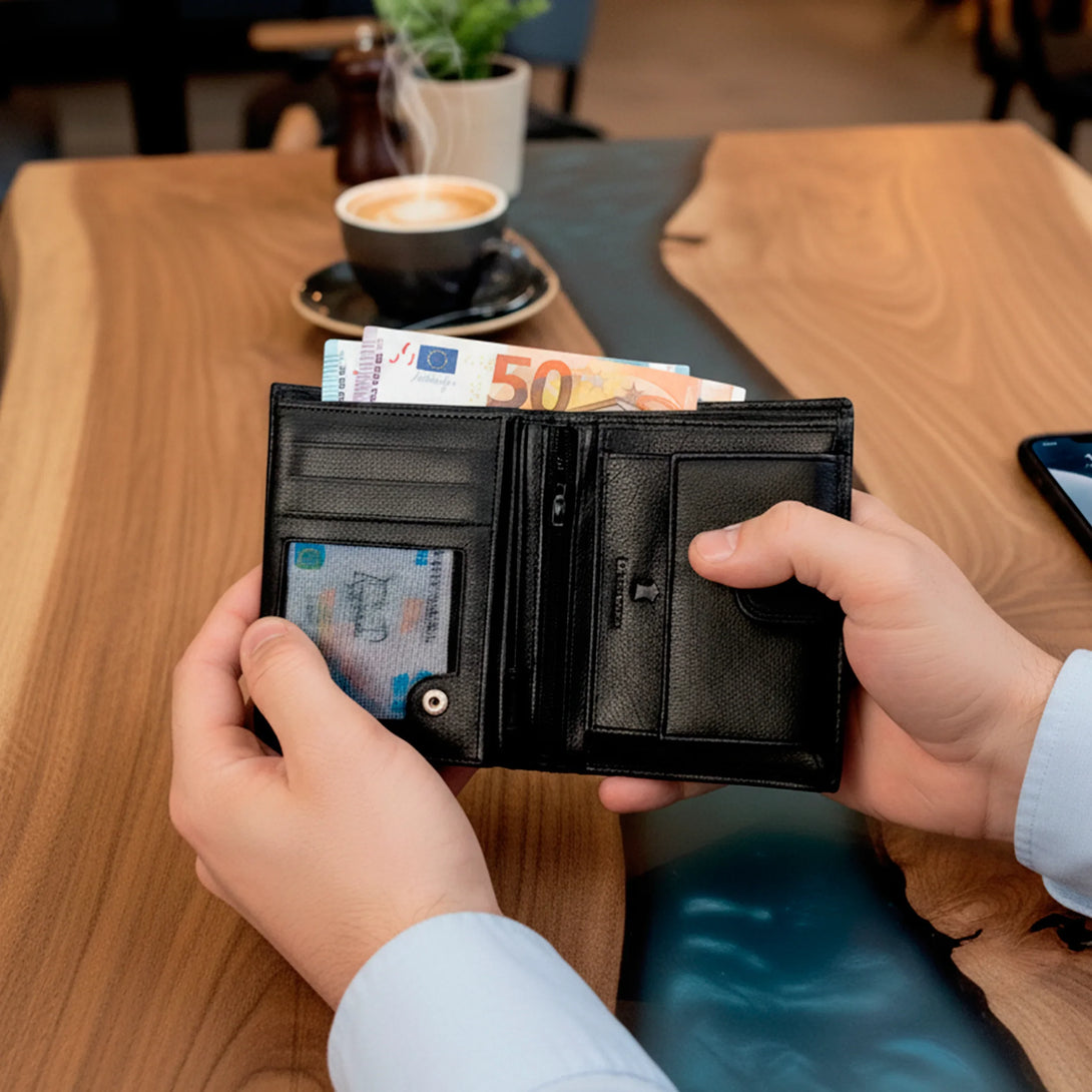 Personalized black leather wallet for men held open with euro bills inside on wooden table